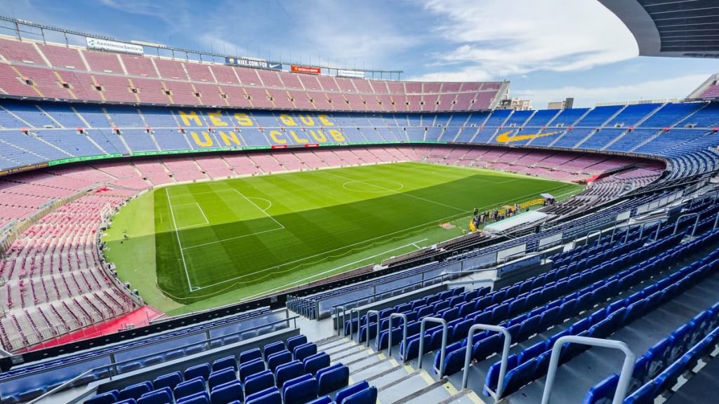 Wide-angle view of the iconic Camp Nou stadium in Barcelona, Spain, featuring its vibrant seating and green field.