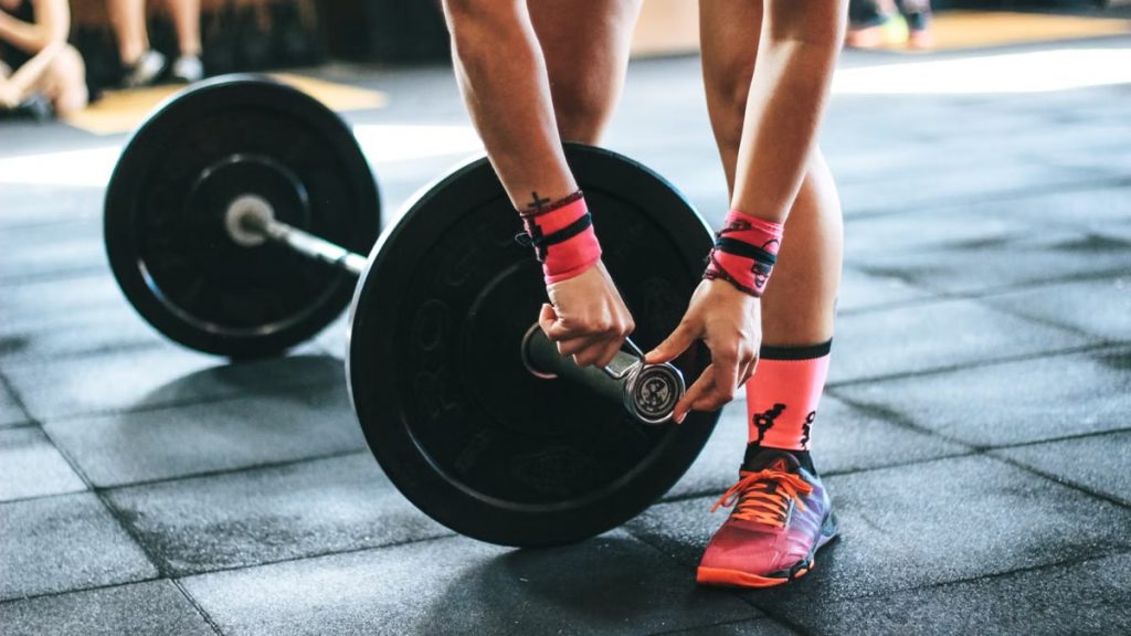 Athlete tightening barbell plates in a gym, emphasizing fitness and strength.